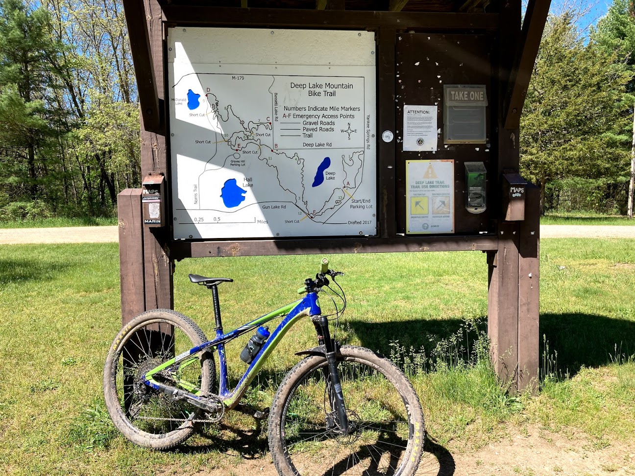 Blue and Green bike leaning against the Yankee Springs Trailhead sign